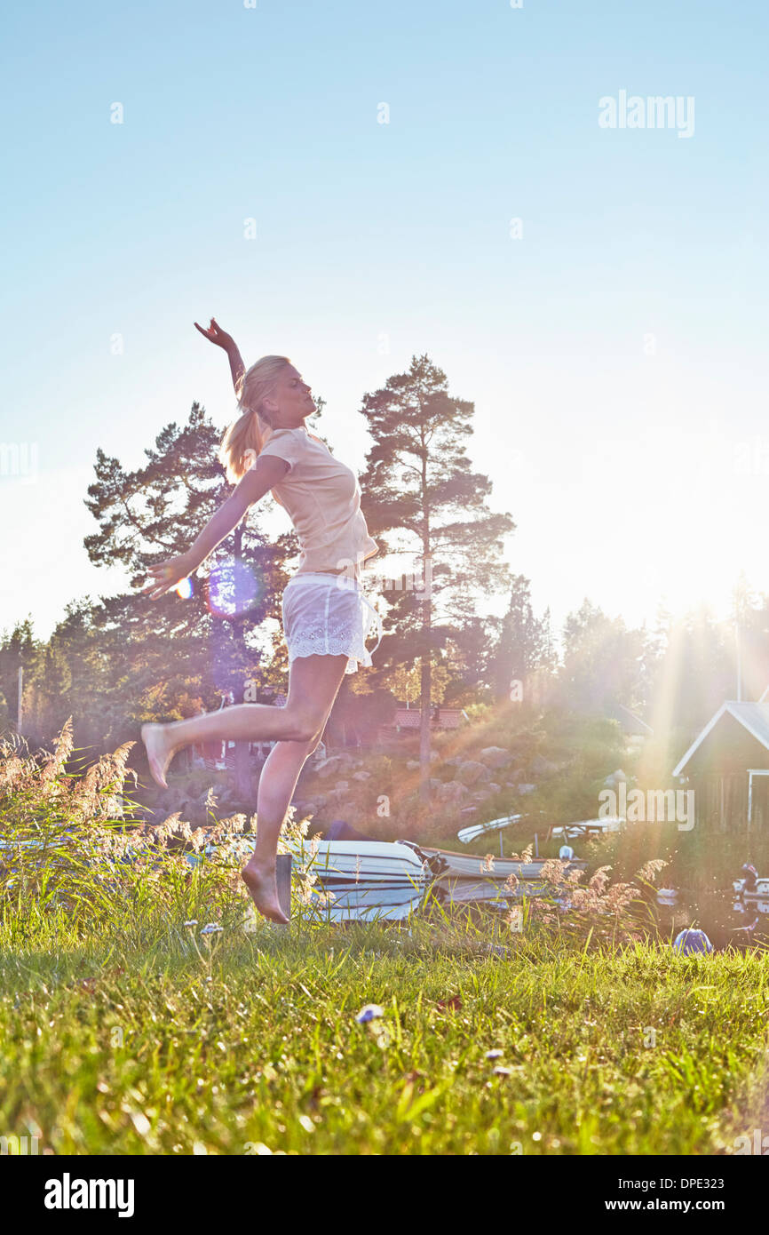 Junge Frau springt neben dem See, Hotels, Schweden Stockfoto