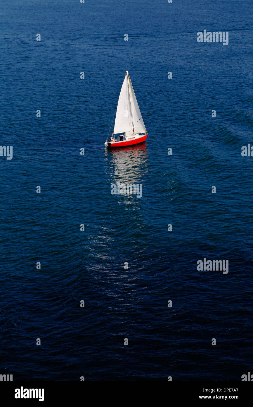 Zusammensetzung von einem roten Segelboot und einem winzigen roten Motorboot Stockfoto