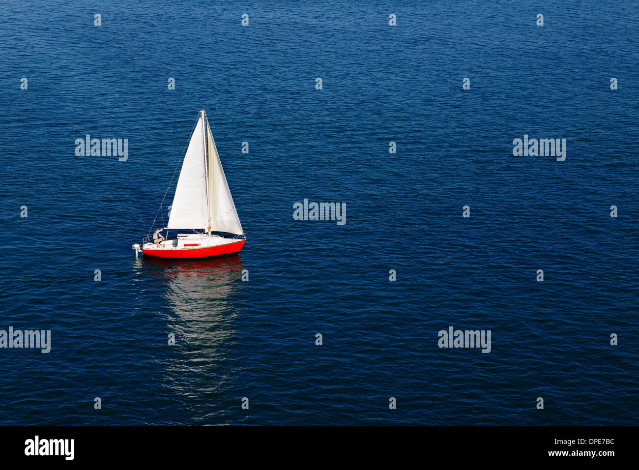 Zusammensetzung von einem roten Segelboot und einem winzigen roten Motorboot Stockfoto