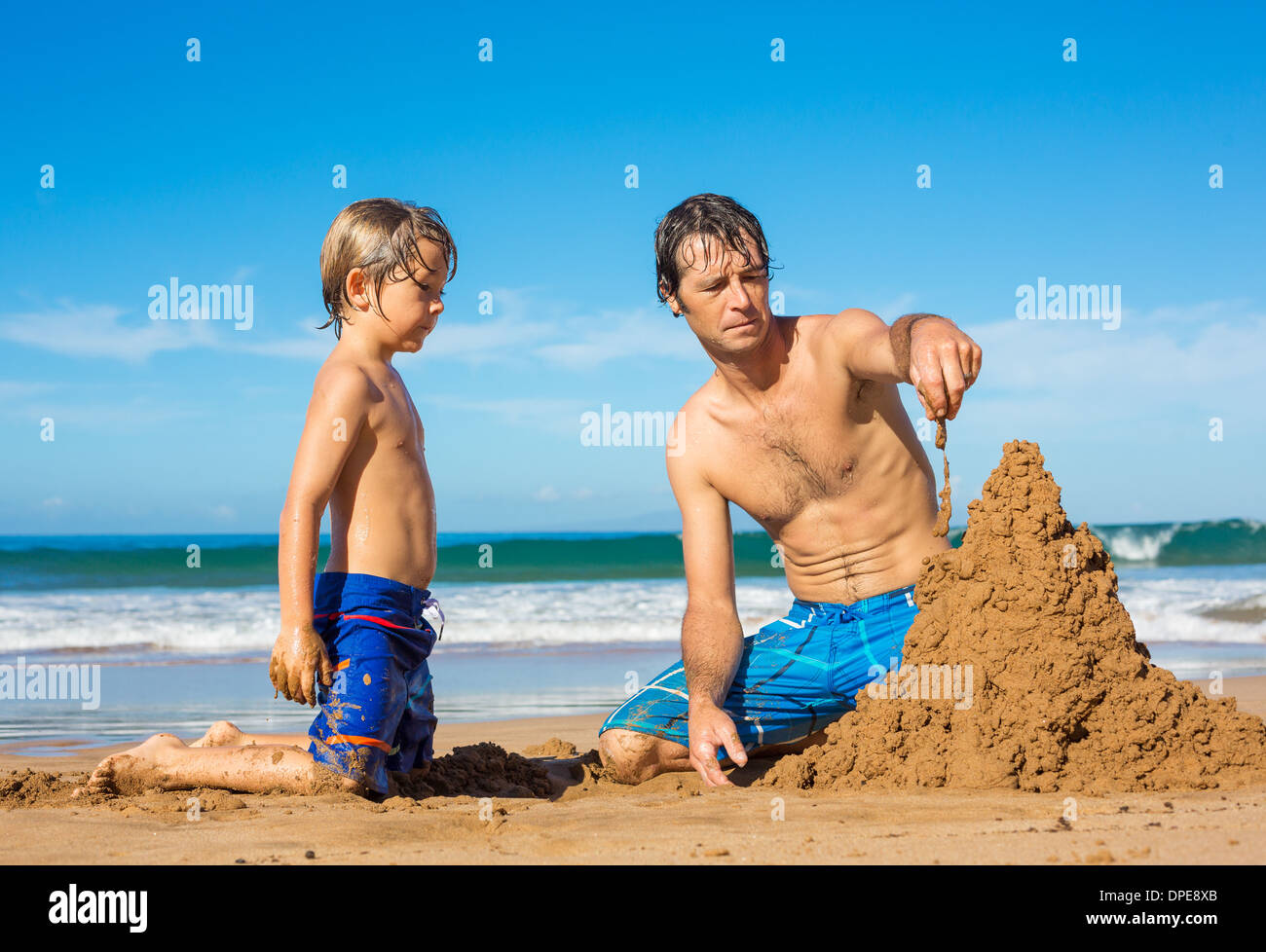 Vater und Sohn spielen zusammen im Sand am tropischen Strand, Gebäude Sand castle Stockfoto