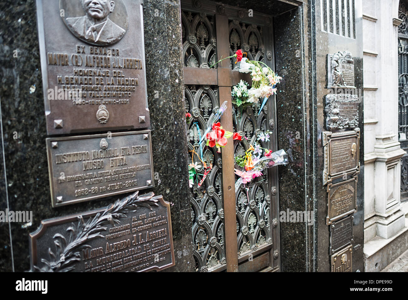Evita Perón Grabblumen Recoleta Friedhof Buenos Aires // BUENOS AIRES, Argentinien — frische Blumen markieren das Gewölbe der Familie Duarte auf dem Recoleta Friedhof (Cementerio de la Recoleta), wo Eva 'Evita' Perón ruht. Das Grab der ehemaligen First Lady Argentiniens, die 1952 starb, ist ein Wallfahrtsort für Besucher und hingebungsvolle Anhänger. Die bescheidene Bronzetür des Duarte Mausoleums steht im Kontrast zur kunstvollen Architektur, die für diesen historischen Friedhof typisch ist. Stockfoto