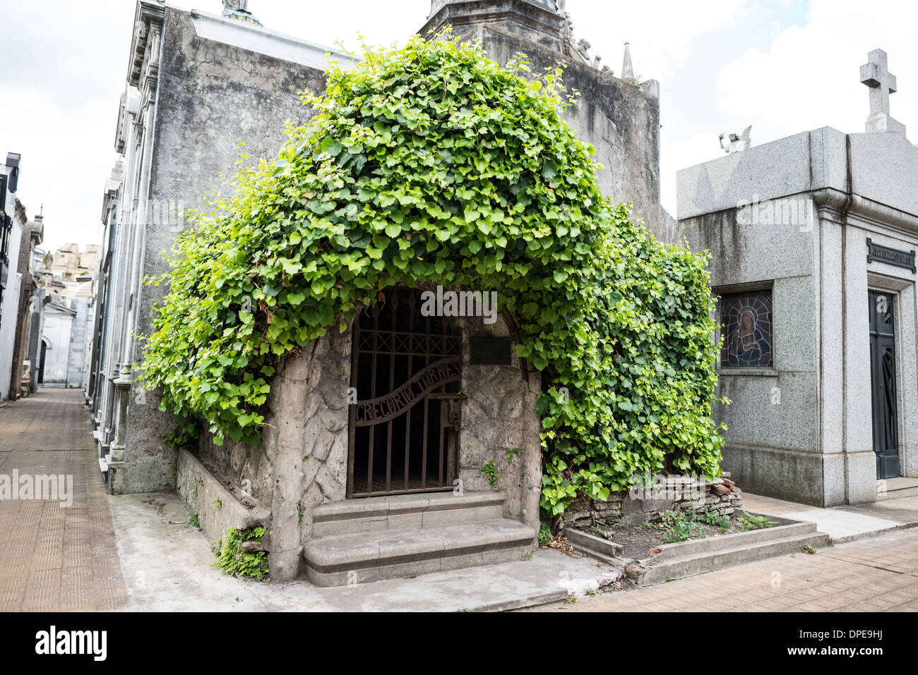 BUENOS AIRES, Argentinien – Ein Mausoleum aus Stein auf dem Friedhof Recoleta (Cementerio de la Recoleta) steht teilweise mit Kletterweben bedeckt. Das natürliche Wachstum bildet einen auffälligen Kontrast zur formalen Architektur und zeigt, wie die Natur mit den historischen Strukturen des Friedhofs interagiert. Diese atmosphärische Integration von Architektur und Vegetation veranschaulicht den sich im Laufe der Zeit entwickelnden Charakter des Friedhofs. Stockfoto