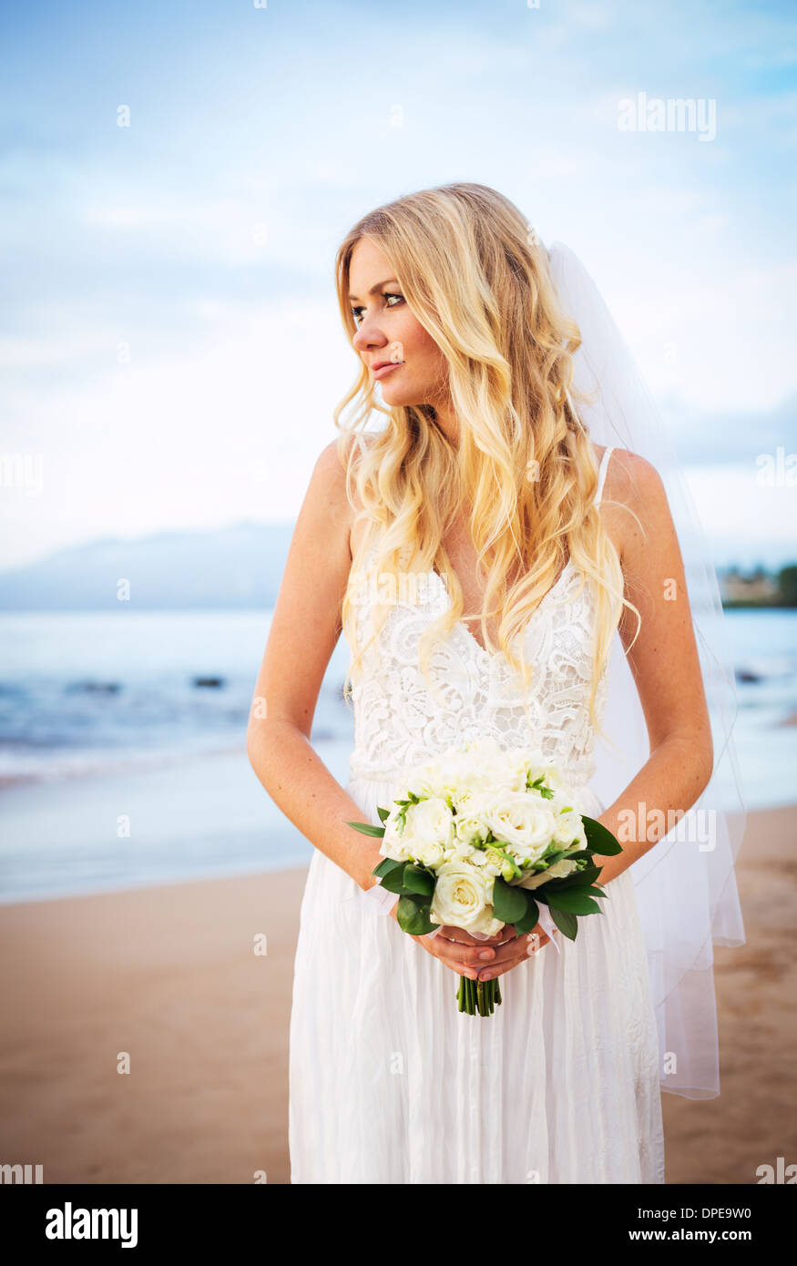 Schöne Braut Hochzeit Kleid mit Blumen bei Sonnenuntergang am schönen tropischen Strand in Hawaii Stockfoto