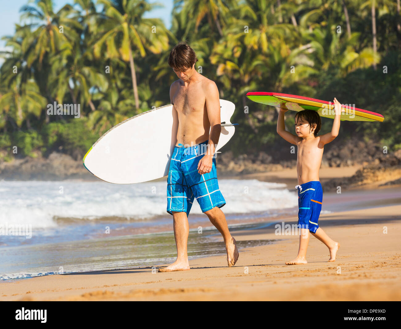 Vater und Sohn gemeinsam am tropischen Strand von Hawaii Surfen Stockfoto