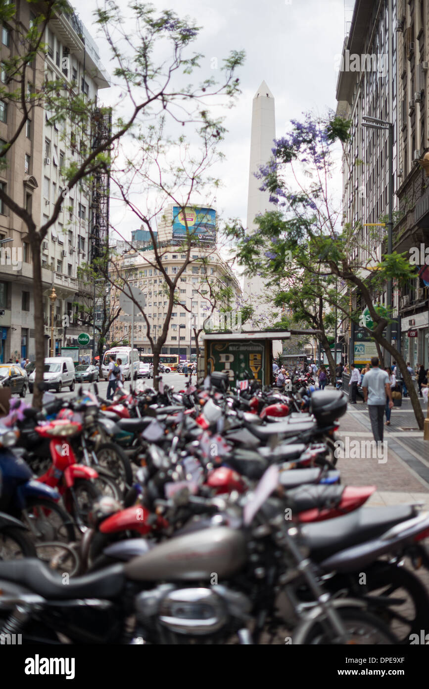 Obelisk Plaza de la República Buenos Aires Argentinien // BUENOS AIRES, Argentinien - der Obelisk (El Obelisco), ein nationales historisches Denkmal und Wahrzeichen von Buenos Aires, steht hoch auf der Plaza de la República in der Innenstadt. Das 67 Meter (220 Fuß) hohe Denkmal wurde 1936 zum Gedenken an das vierte 100-jährige Bestehen der Stadt errichtet und markiert den Ort, an dem die argentinische Flagge in der Hauptstadt zum ersten Mal gehisst wurde. Reihen geparkter Motorräder und Motorroller säumen den Vordergrund und spiegeln das beliebte Transportmittel dieser pulsierenden Metropole wider. Der Obelisk befindet sich an der Kreuzung Stockfoto