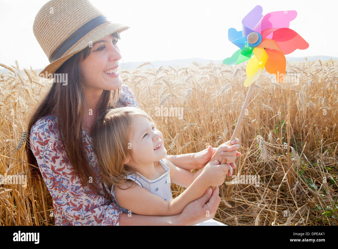 Mutter und Tochter in Weizen Feld Holding Windmühle Stockfoto