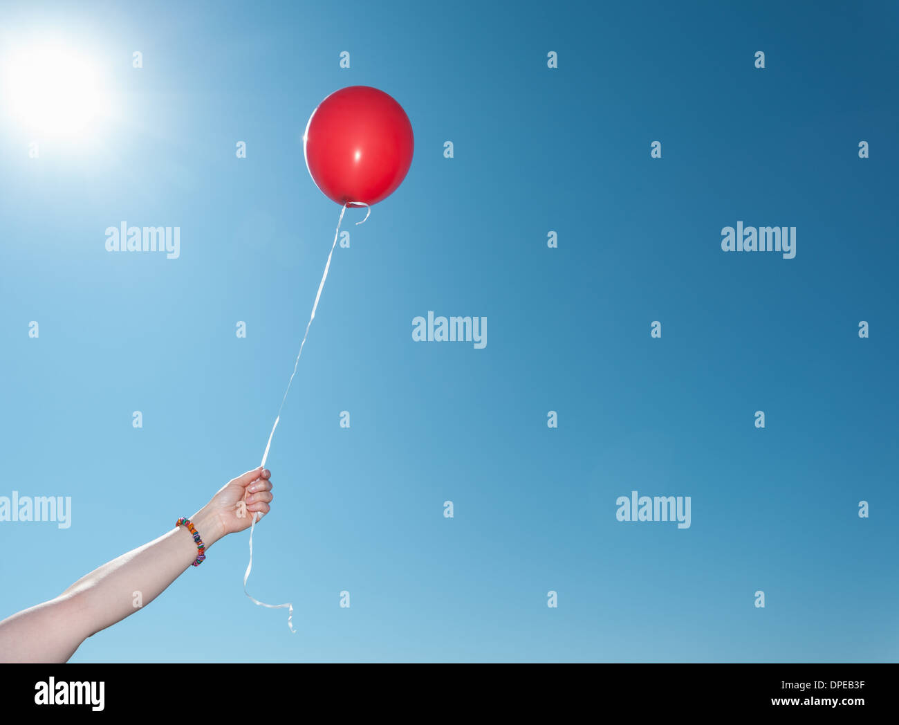 Hand, die einzelnen roten Ballon gegen blauen Himmel Stockfoto