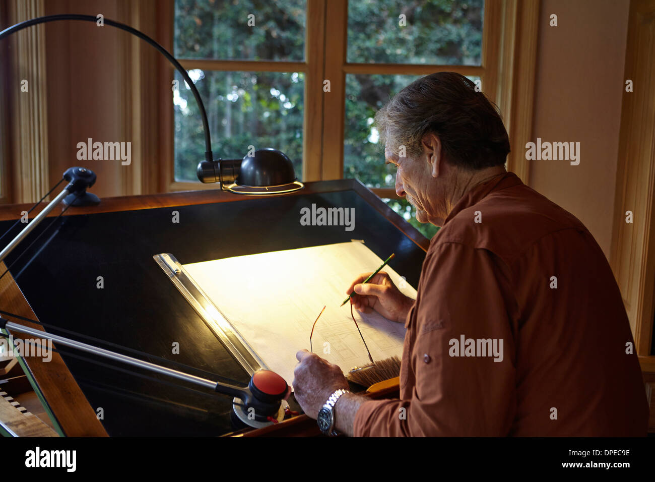 Senior woman an architektonische Zeichnung zu Hause arbeiten Stockfoto