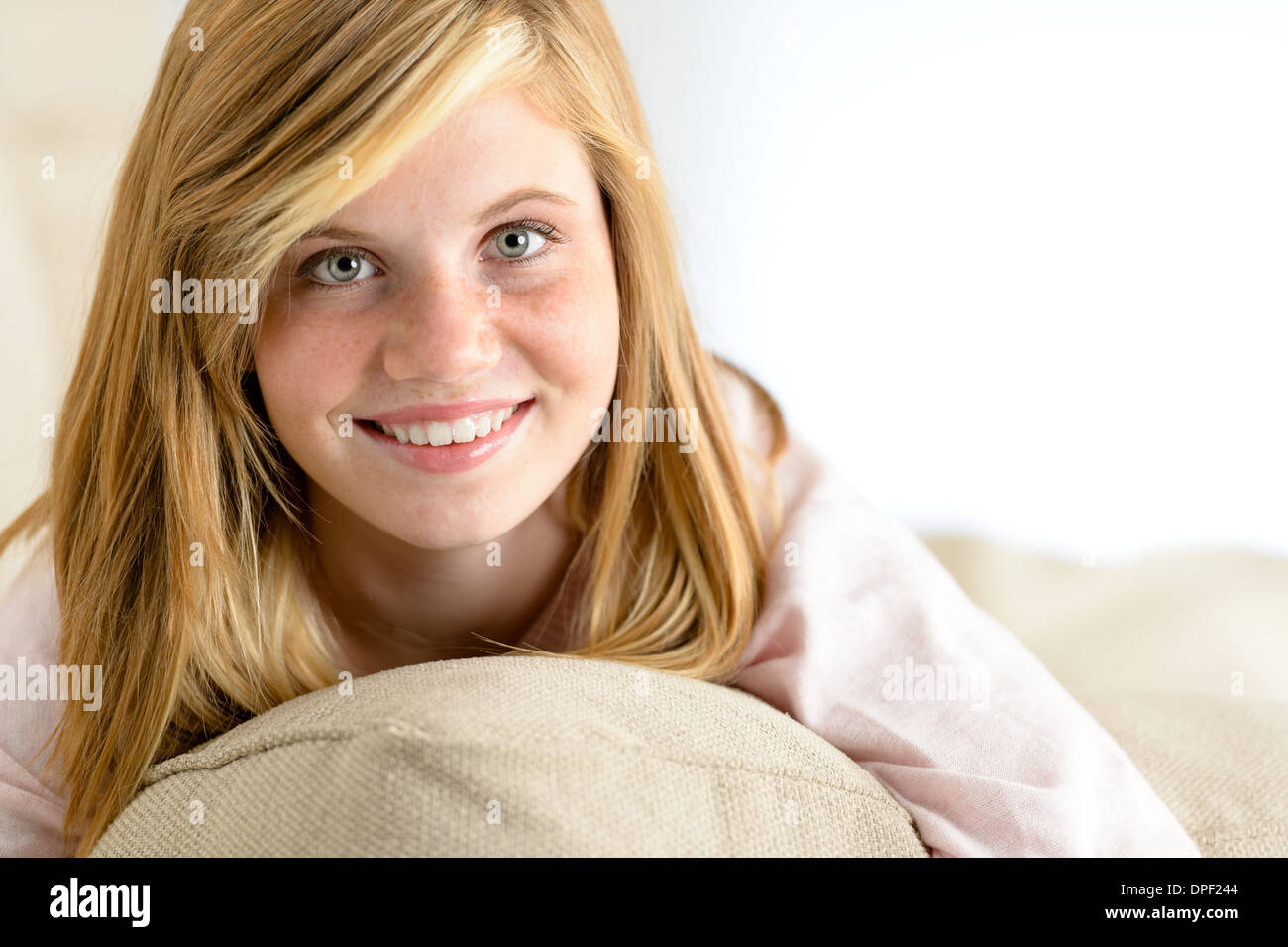 Schöne Teenager-Mädchen liegend auf Kissen, Blick in die Kamera Lächeln Stockfoto