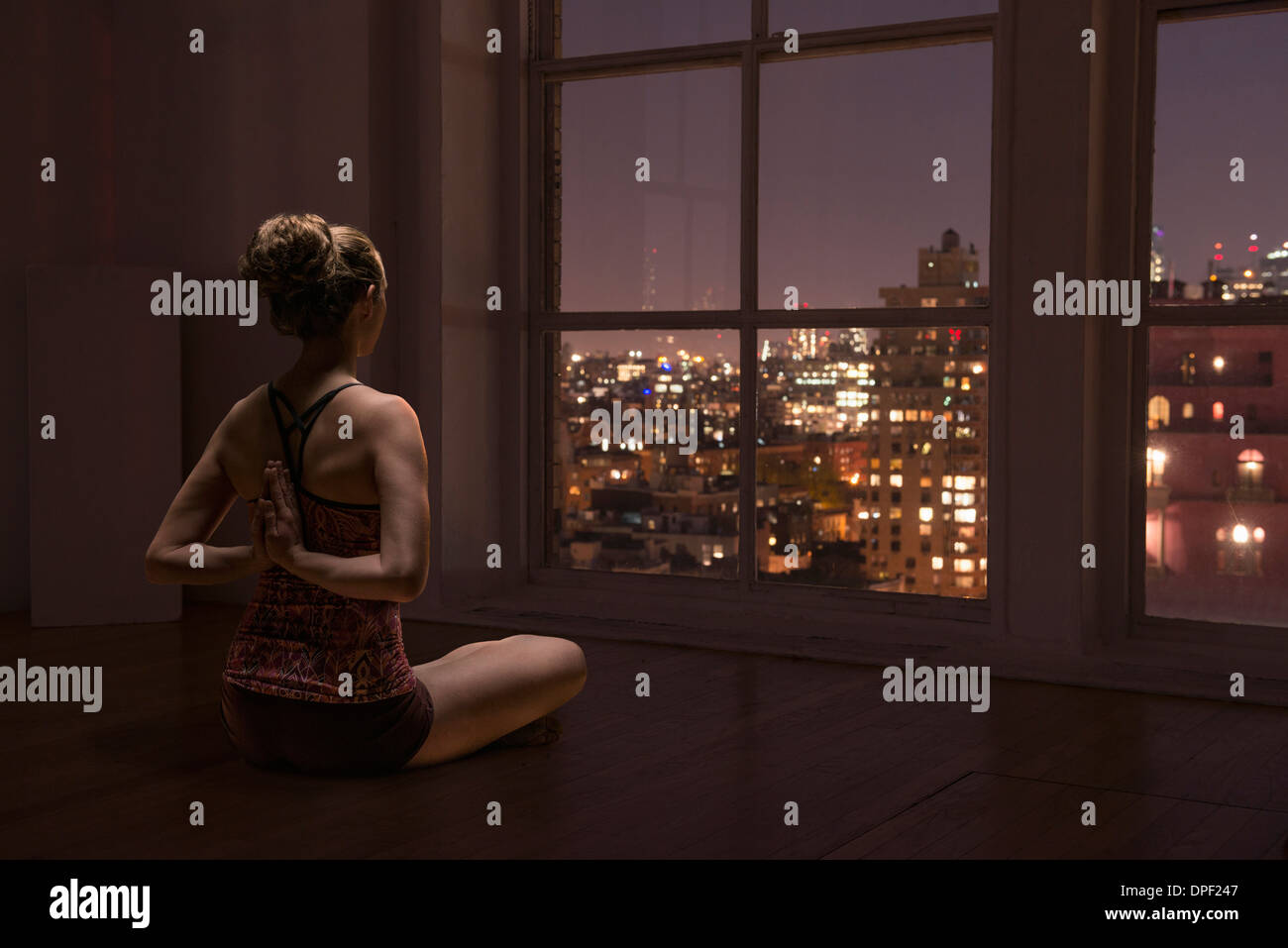 Frau praktizieren Yoga durch Fenster Stockfoto