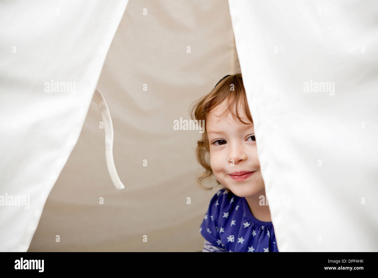 Porträt von weiblichen Kleinkind spähen aus Zelt Stockfoto