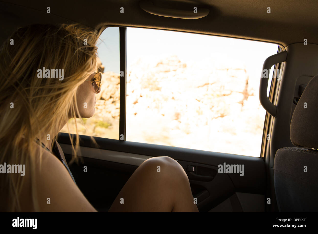 Junge Frau aus Rücksitz Autofenster, Joshua Tree Nationalpark, Kalifornien, USA Stockfoto