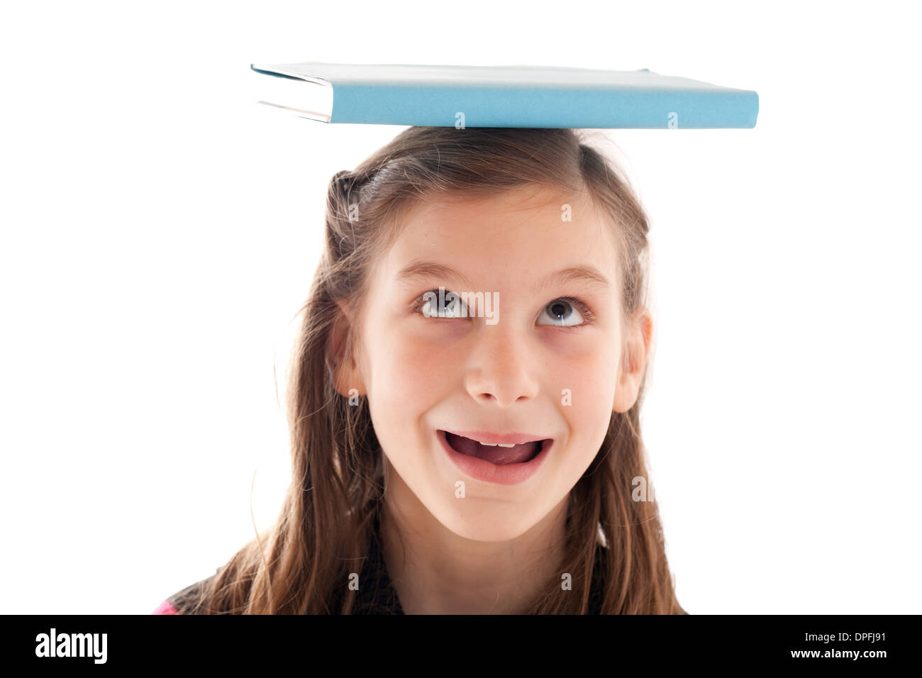 Symbolisches Bild Bildung: lächelndes Mädchen hält ein Buch auf dem Kopf Stockfoto