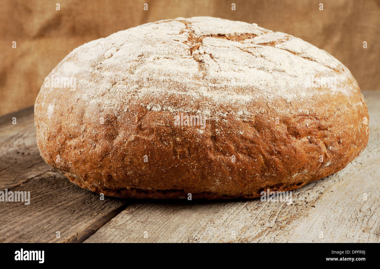 Rundes Laib Schwarzbrot auf einem hölzernen Hintergrund Stockfoto