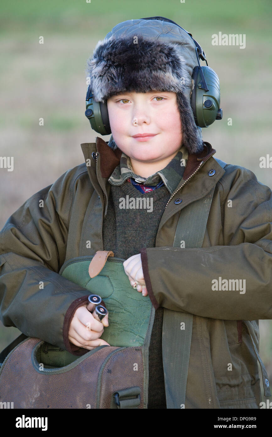 Ein kleiner Junge hält eine Patrone Tasche und Schrotflinte Patronen auf einem Fasan schießen in England Stockfoto