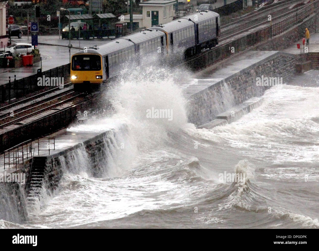 Ein Zug wird durch Wellen zerschlagen, während es Dawlish Bahnhof durchläuft Stockfoto
