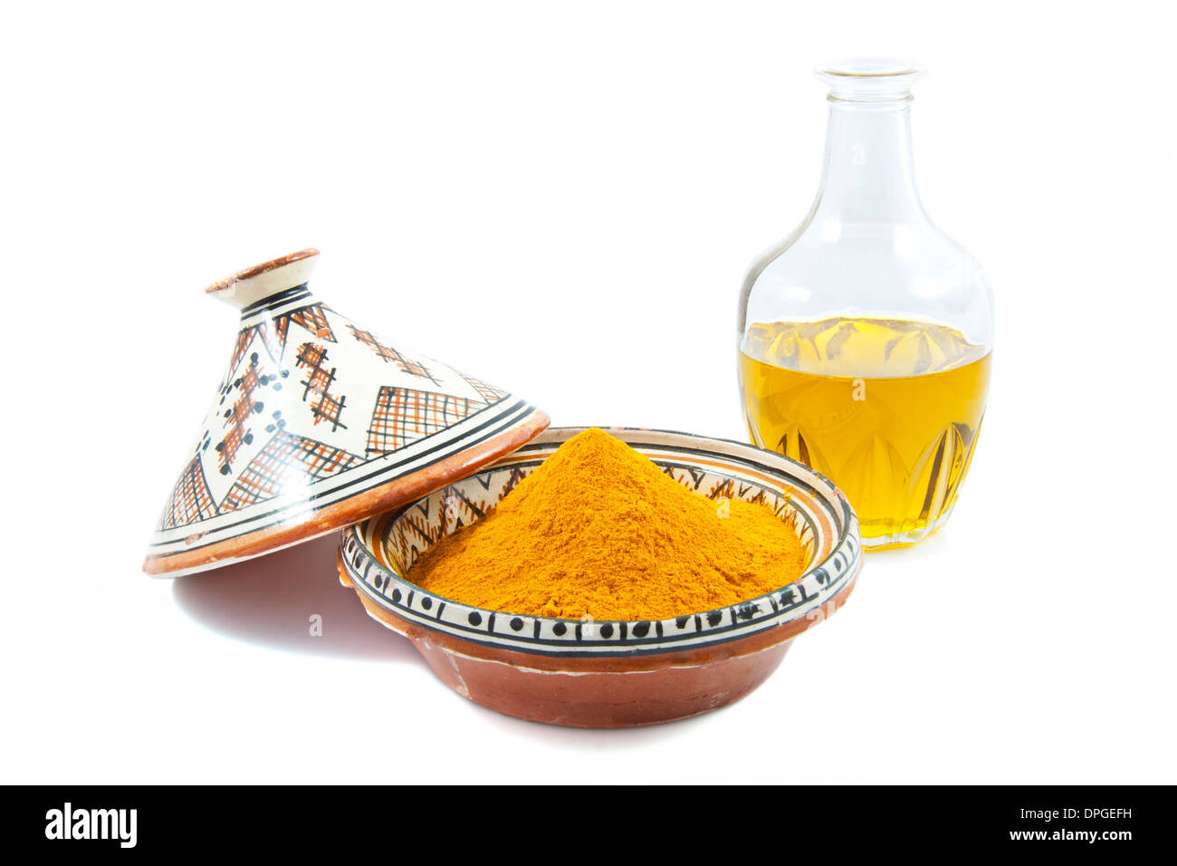 Karaffe mit Olivenöl und einer Tajine gefüllt mit Gewürzen isoliert auf weiß Stockfoto