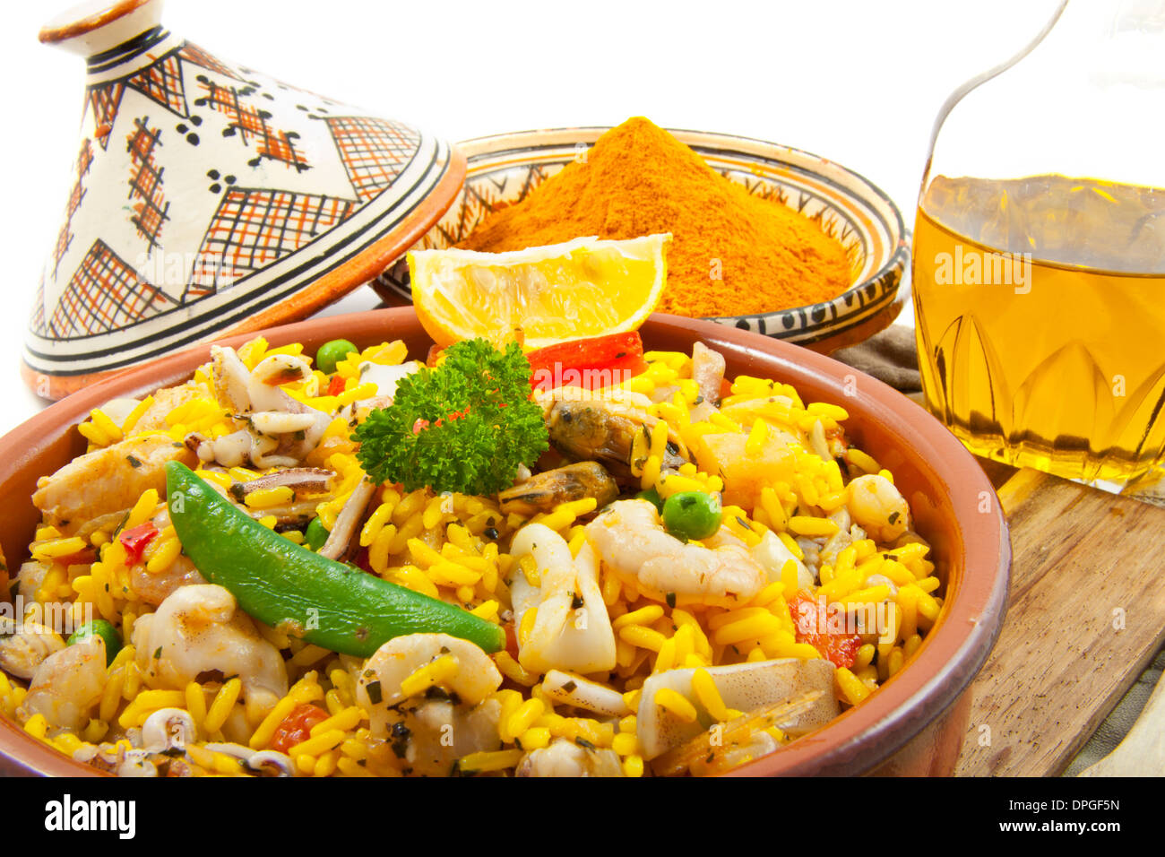 Paella mit Safran und Öl auf einem Holzbrett über weiß Stockfoto