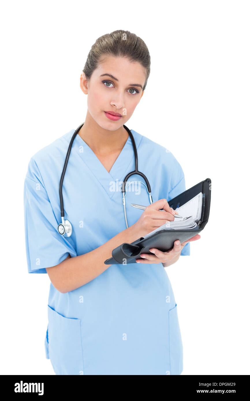 Heck braunen Haaren Krankenschwester in blau scheuert füllen eine agenda Stockfoto