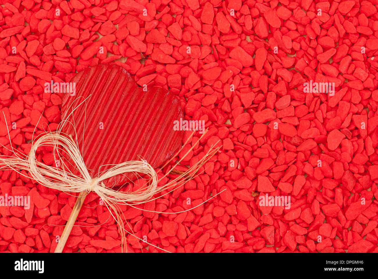 Rotes Herz unter roten Kieselsteinen Hintergrund Stockfoto
