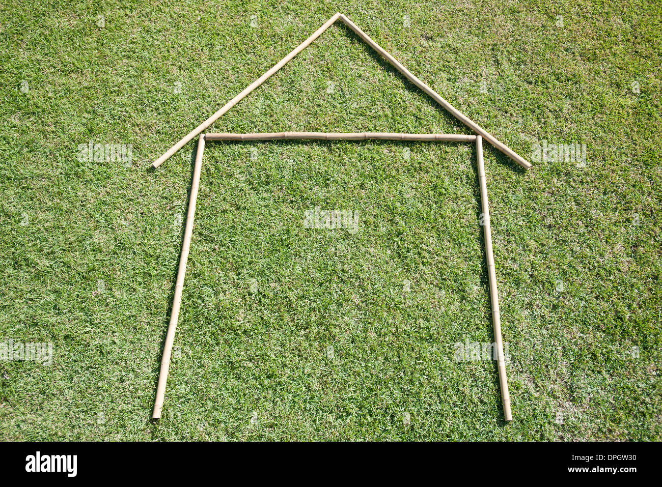 Stöcke angeordnet im Haus Form auf Rasen Stockfoto