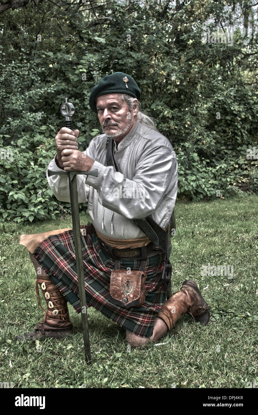 Schottische Mann gekleidet in einem Kilt kniend mit seinem Schwert HDR Stockfoto