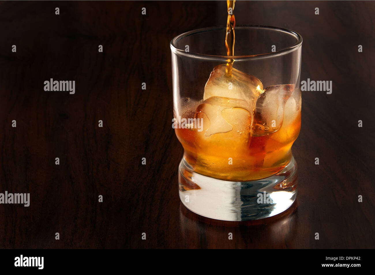 Whisky in ein Glas mit Eis drin auf einem dunklen Hintergrund aus Holz Stockfoto