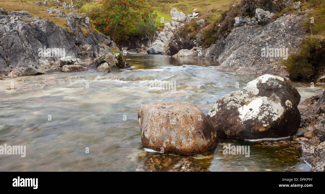 Gebirgsbach in Schottland aufgenommen mit Langzeitbelichtung und Schwerpunkt auf den Felsen im Vordergrund. Stockfoto
