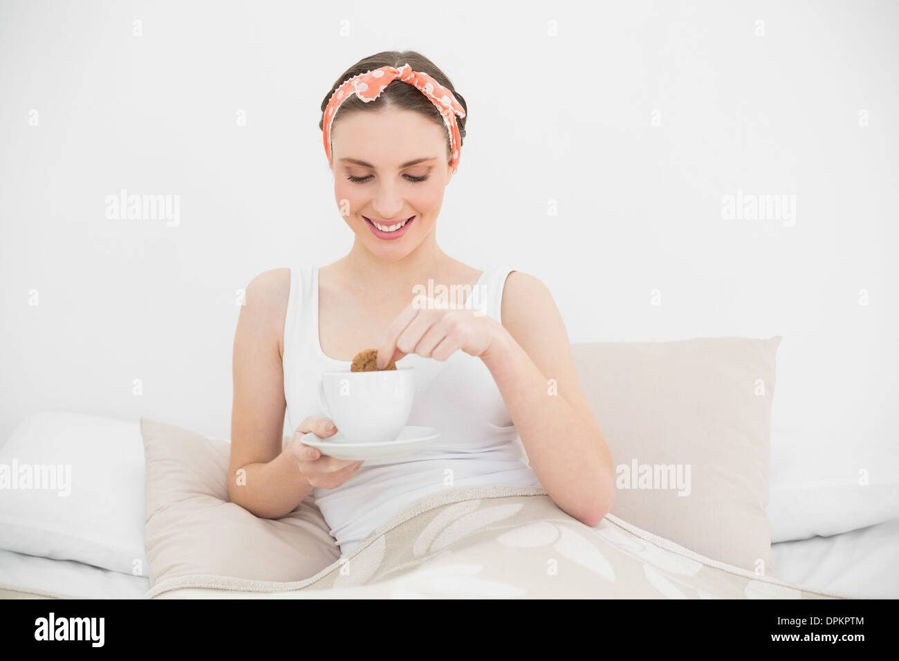 Lächelnde Frau eintauchen einen Keks in ihren Kaffee Stockfoto