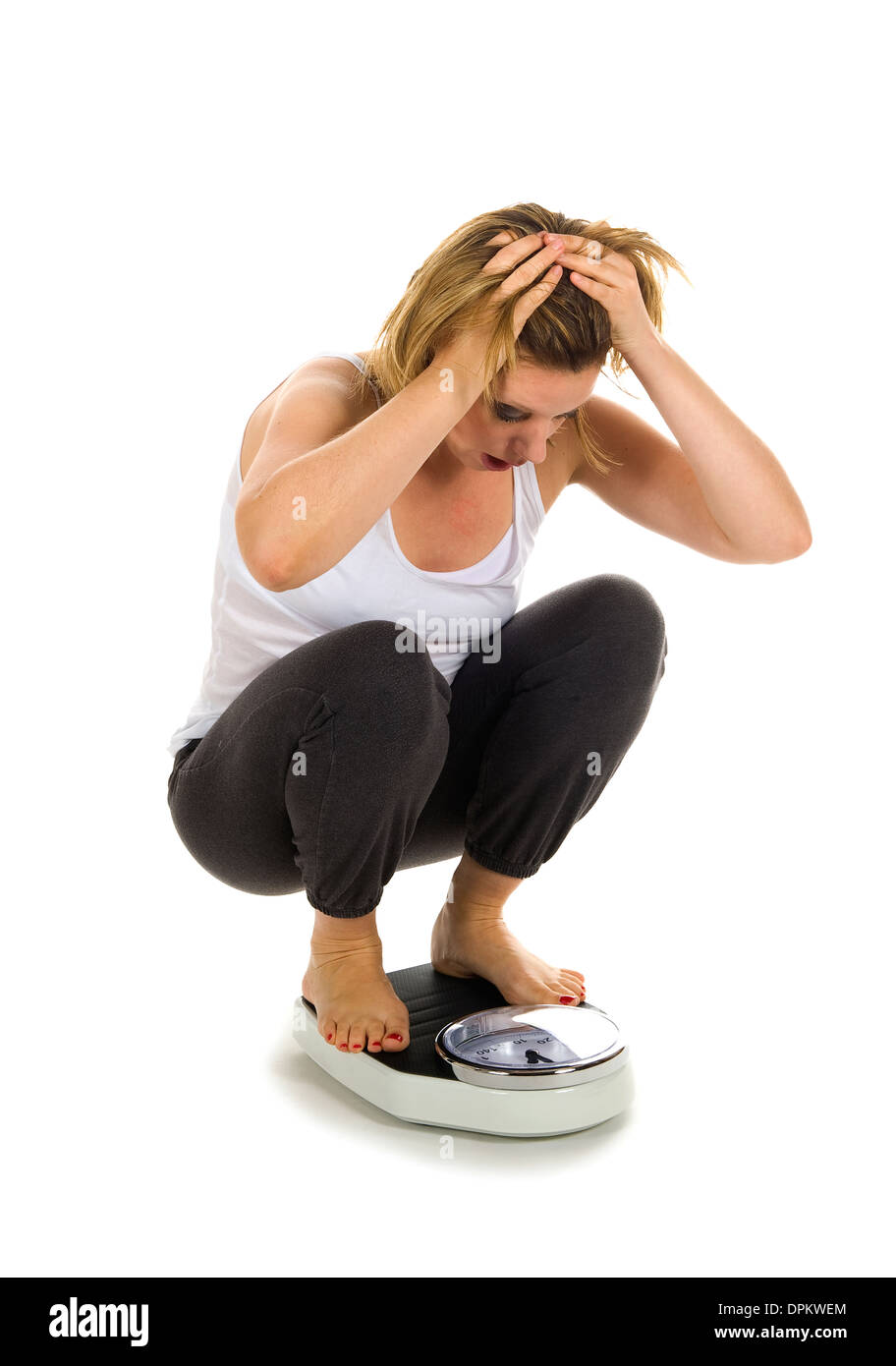 Eine Frau sitzt auf einer Waage und ist besorgt über Het Gewicht Stockfoto