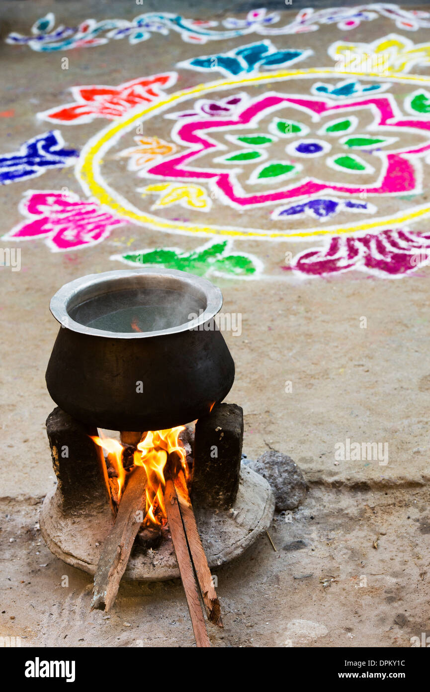 Kochendes Wasser auf offenem Feuer in einem ländlichen indischen Dorf vor einem Rangoli design während des Festivals von sankranthi. Andhra Pradesh, Indien Stockfoto