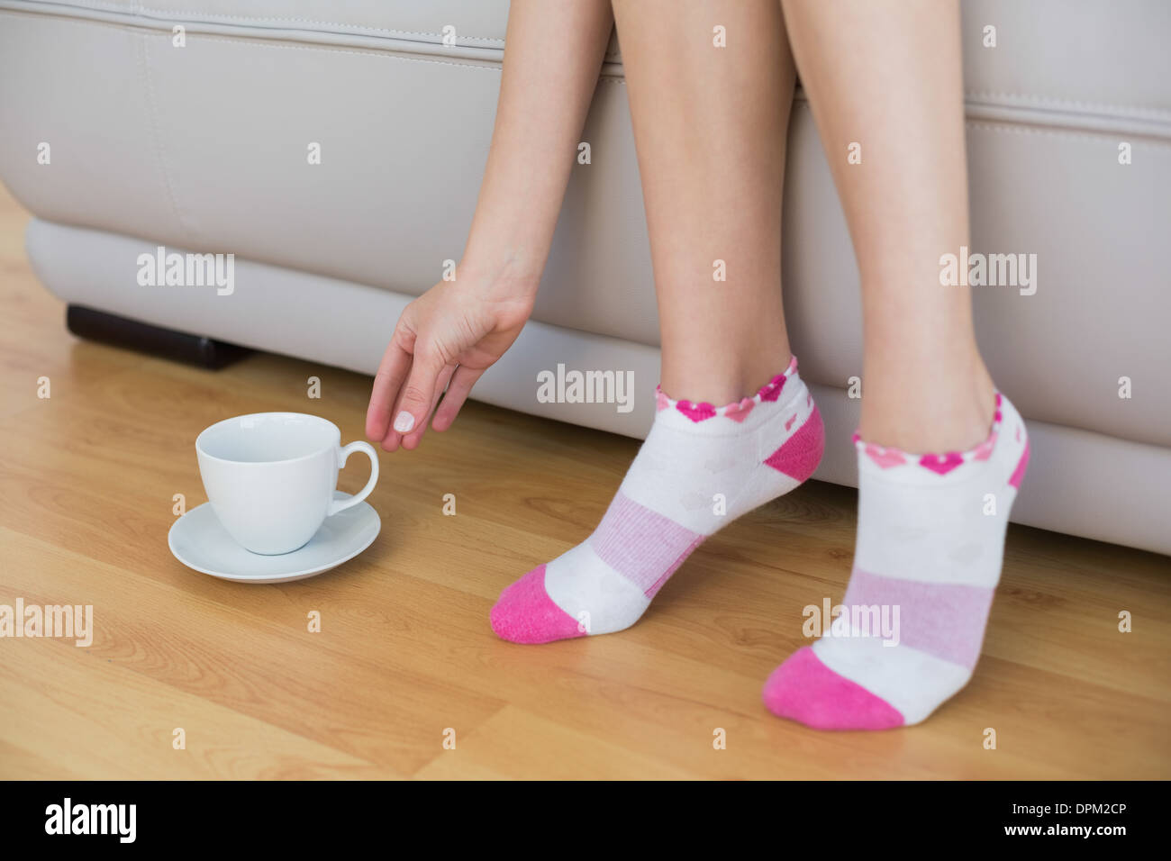 Junge schlanke Frau trägt rosa Socken auf couch Stockfoto