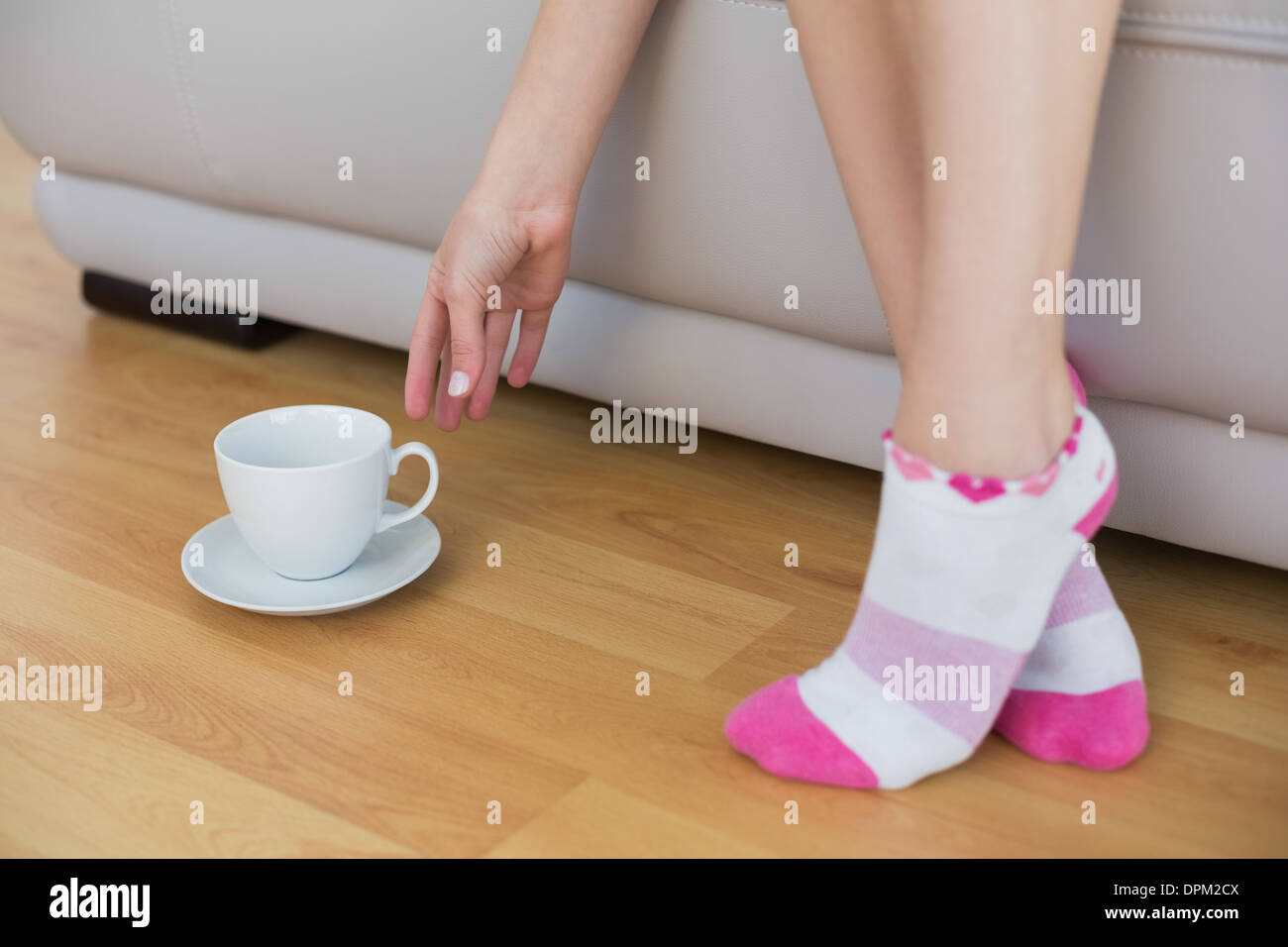 Junge schlanke Frau trägt rosa Socken erreichen für eine Tasse Stockfoto