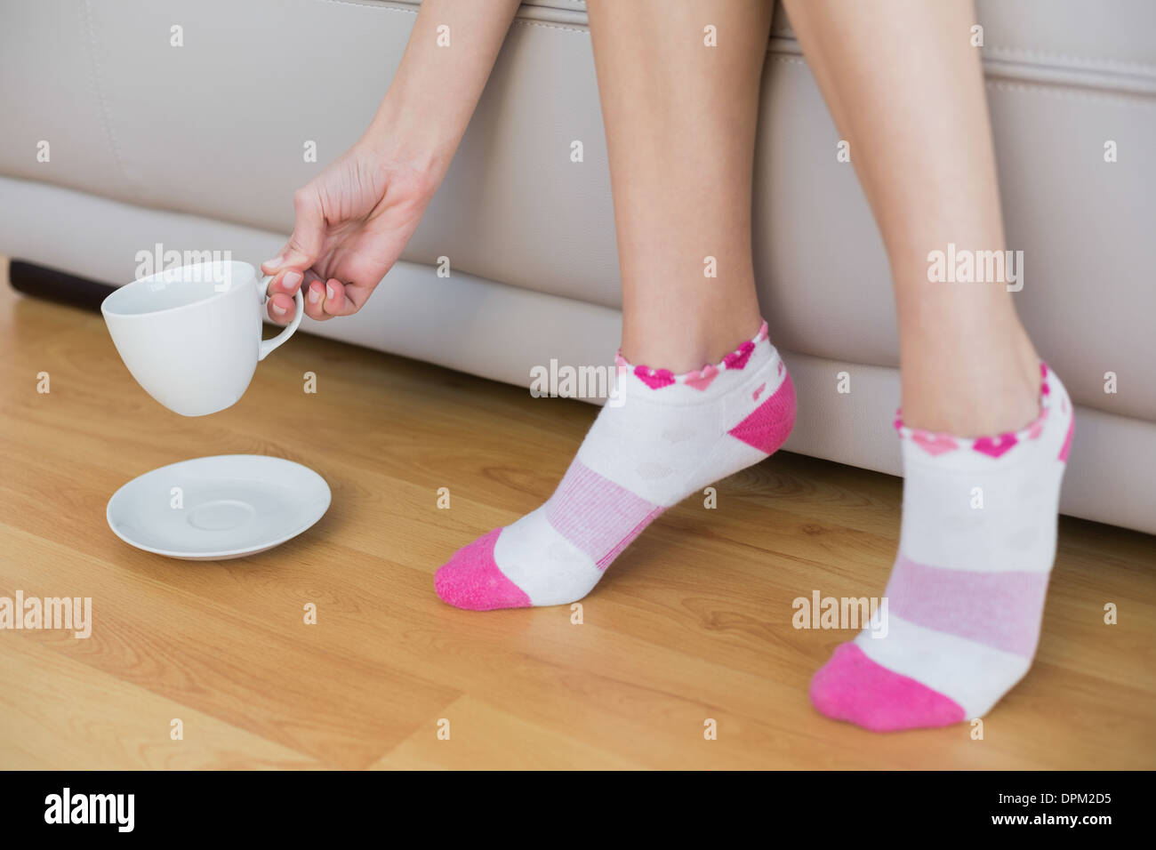 Junge Frau trägt rosa Socken hält eine Tasse Stockfoto