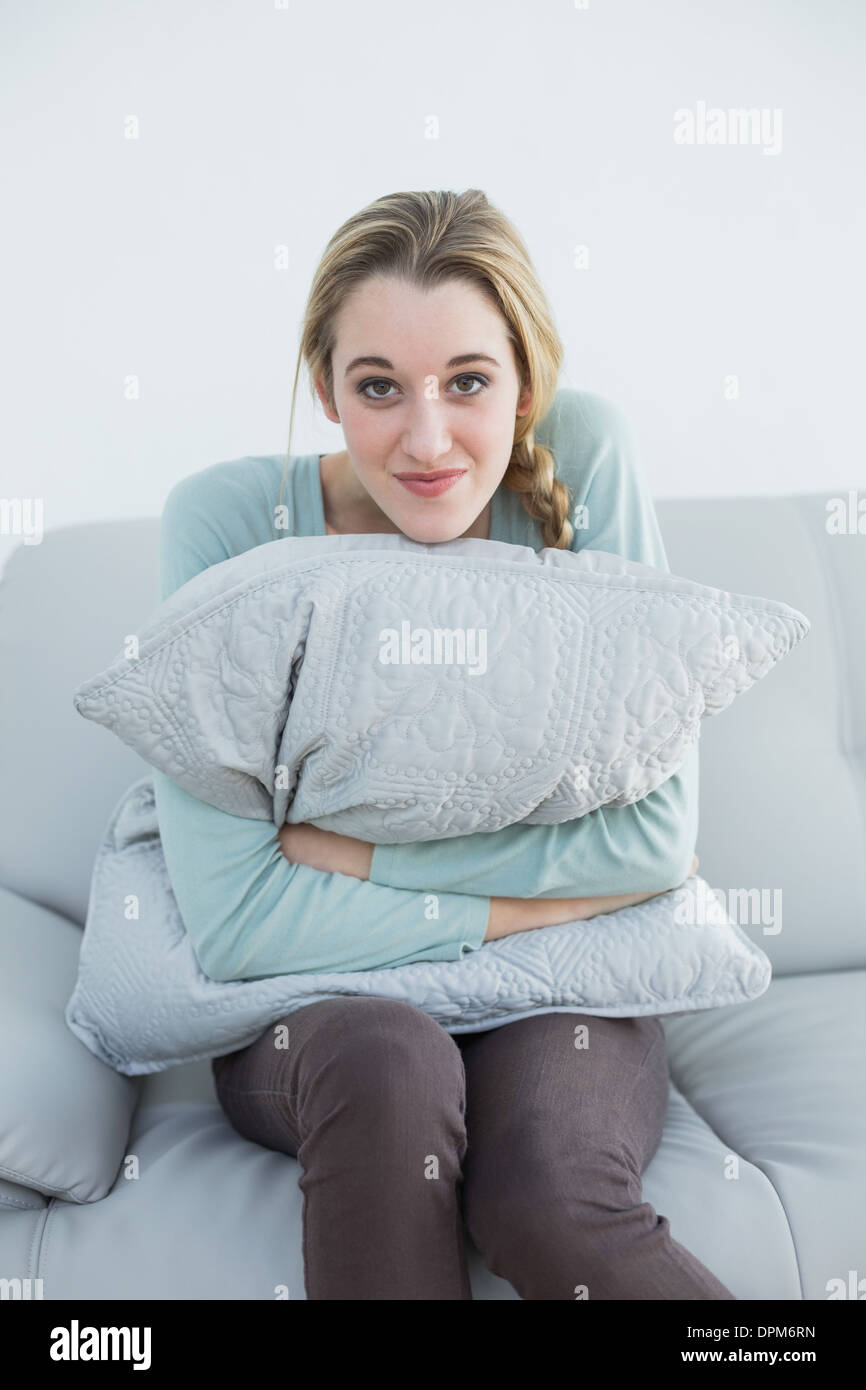 Schöne süße Frau sitzt auf der Couch kuscheln mit einem Kissen  Stockfotografie - Alamy