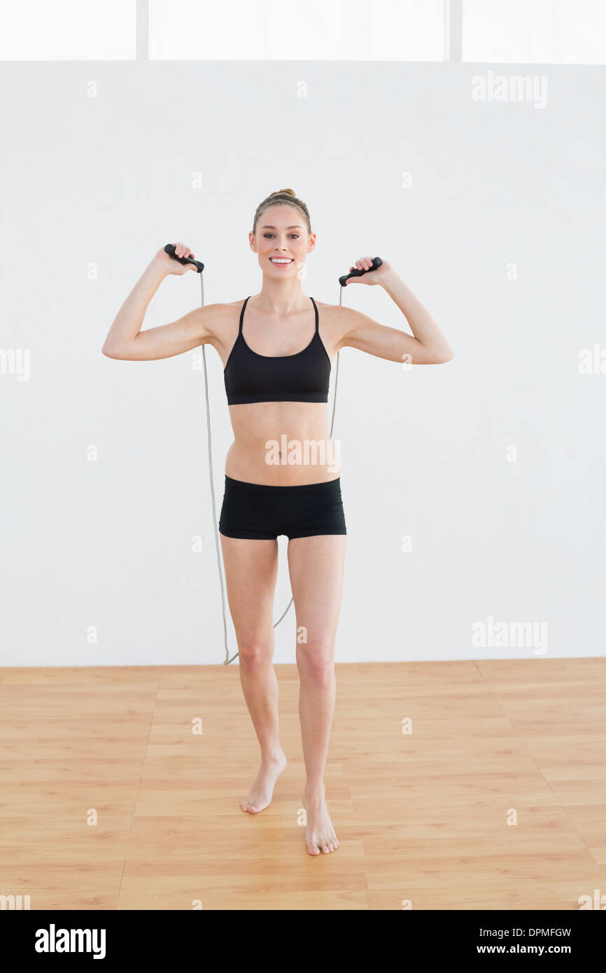 Freudiger schlanke Frau hält ein Seil zum überspringen Stockfoto