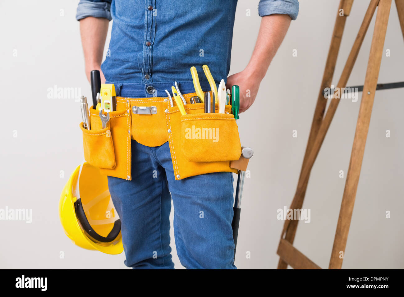 Mittleren Bereich der einen Handwerker mit Werkzeuggürtel und Schutzhelm Stockfoto