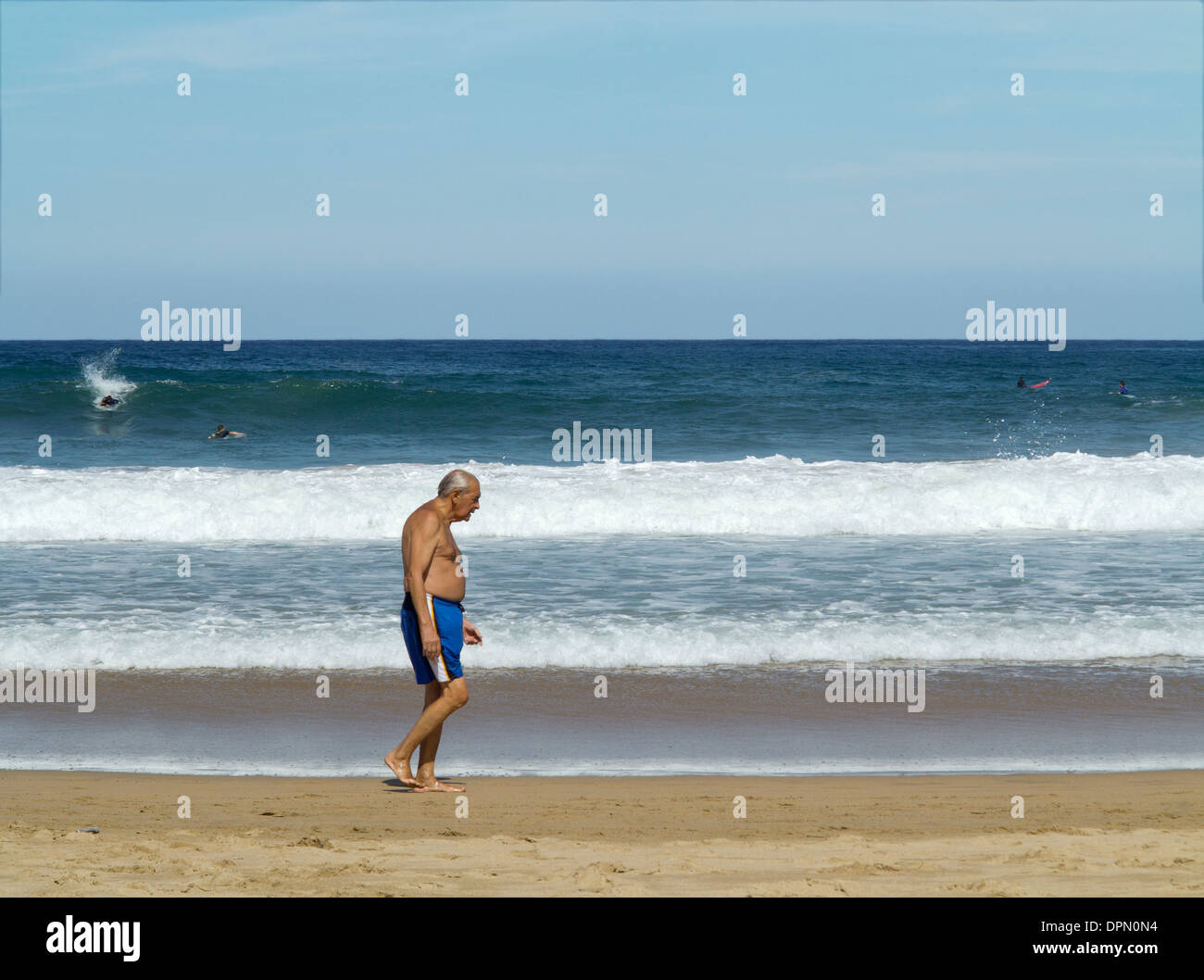 Ältere Mann in Badeshorts Spaziergänge am Strand, Wellen am Ufer am Strand Zurriola, San Sebastian, Spanien Stockfoto