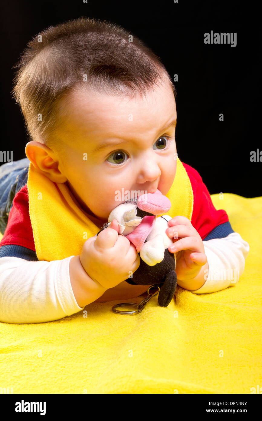 Baby Boy mit Spielzeug auf gelben Decke Stockfoto