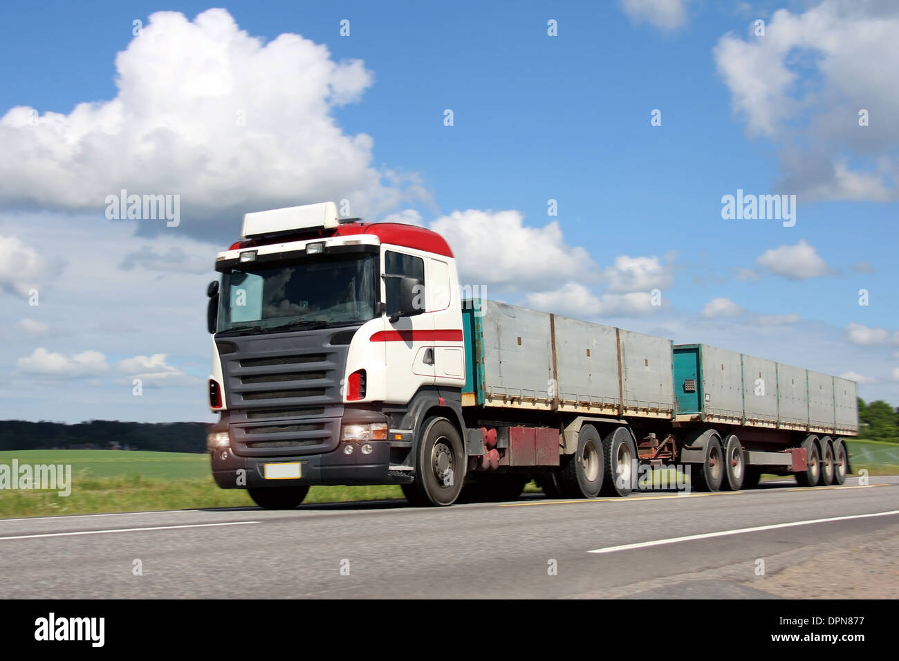 Volle Anhänger lange Transport-LKW auf der Straße, die Fahrt durch die Landschaft im Sommer, Bewegungsunschärfe auf den Hintergrund. Stockfoto