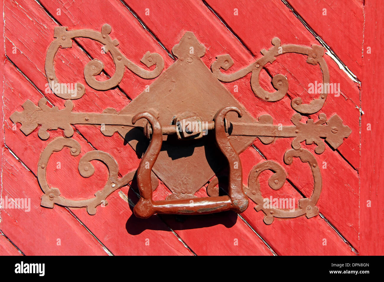 Nahaufnahme von einer kunstvollen antiken Türgriff auf eine rote Holztür. Stockfoto