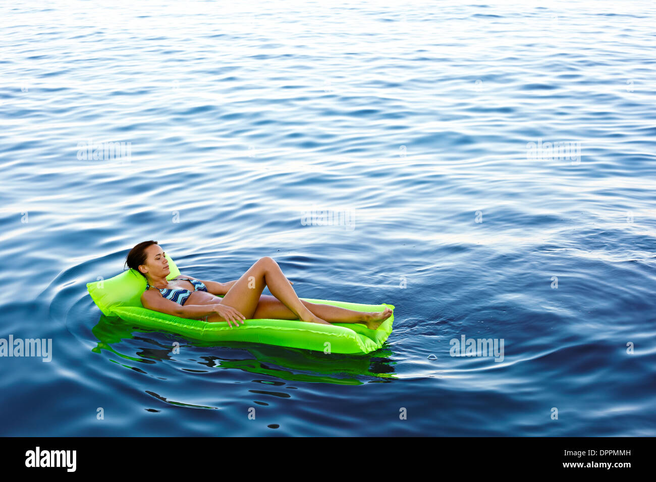 Mädchen auf einer schwimmenden Lilo im Wasser Stockfoto