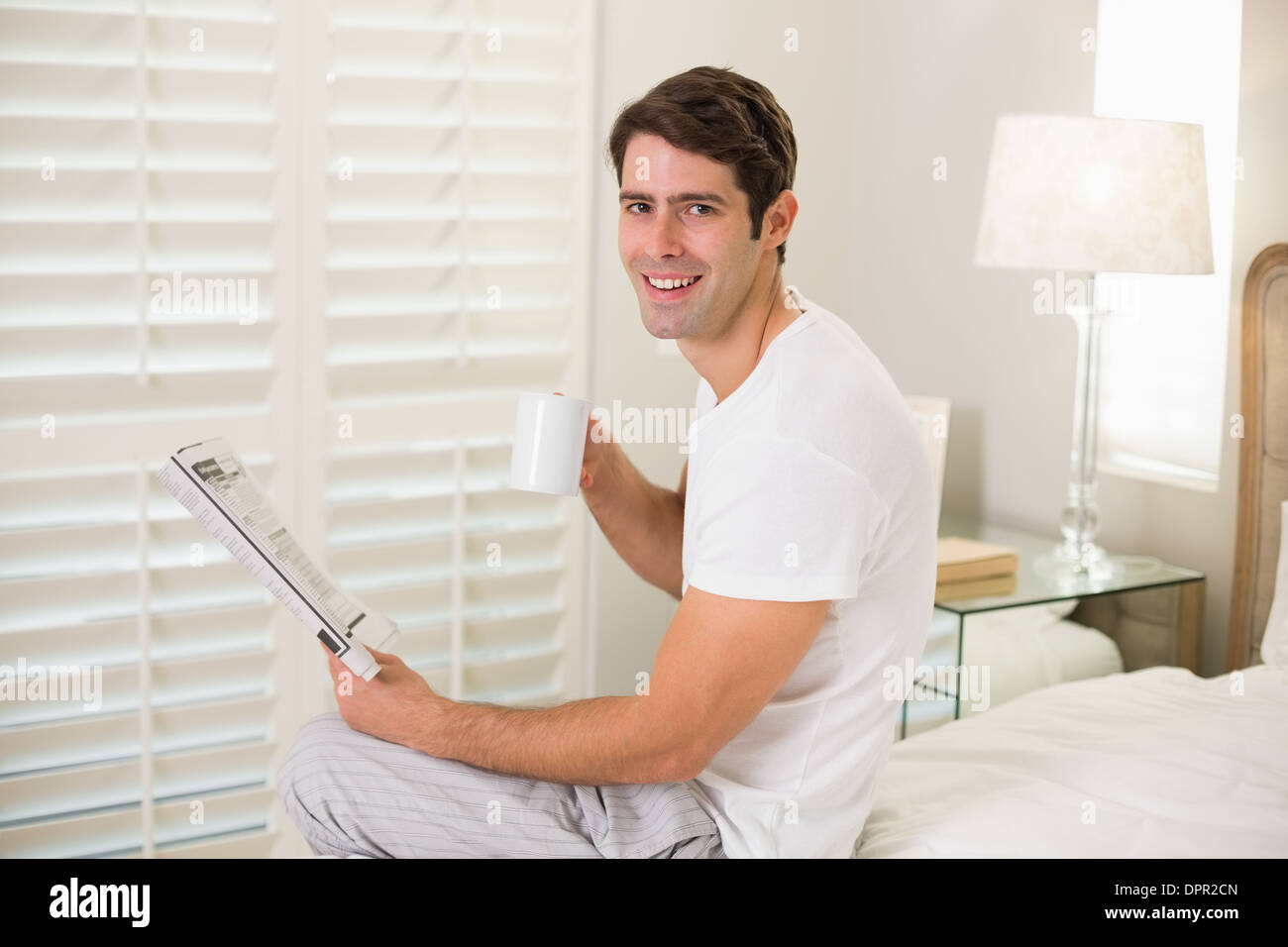 Lächelnd Mann mit Kaffeetasse, lesen Zeitung Stockfoto