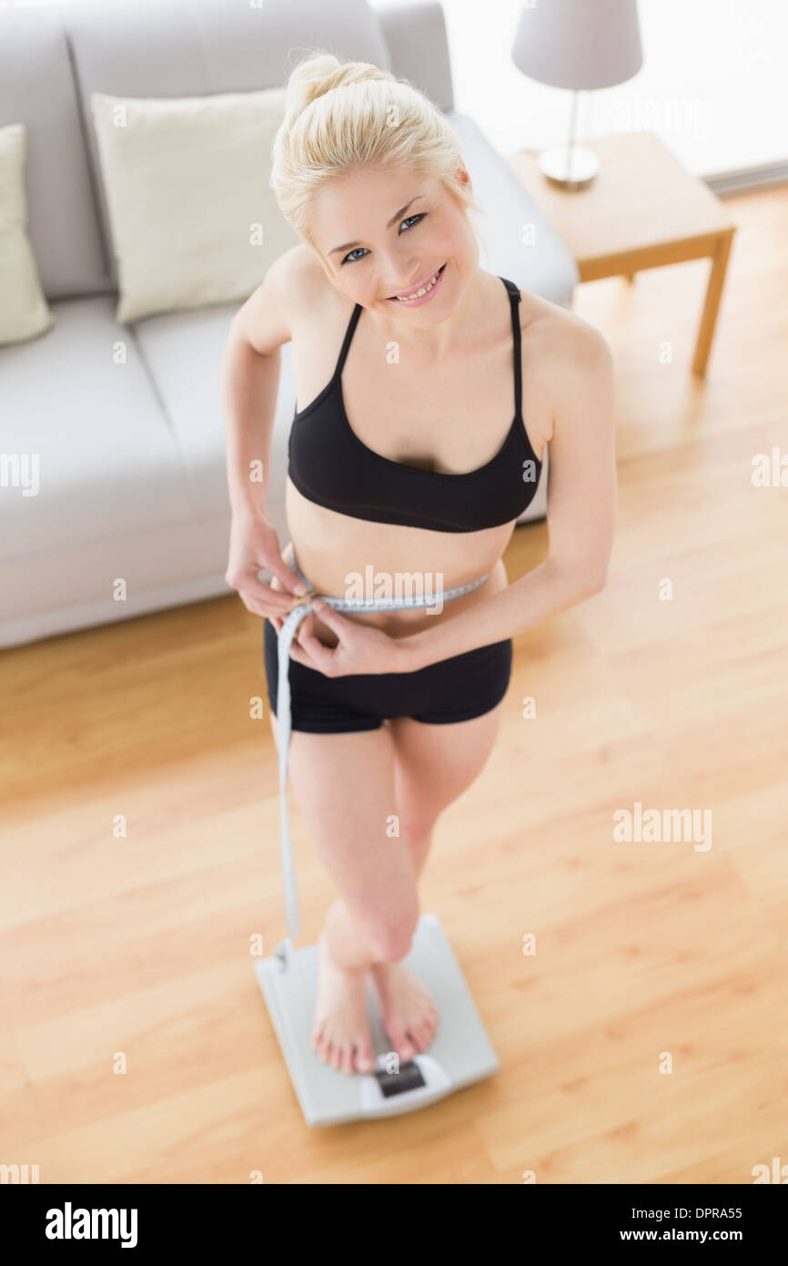 Frau in der Sportswear im Maßstab messen Taille im Fitness-studio Stockfoto