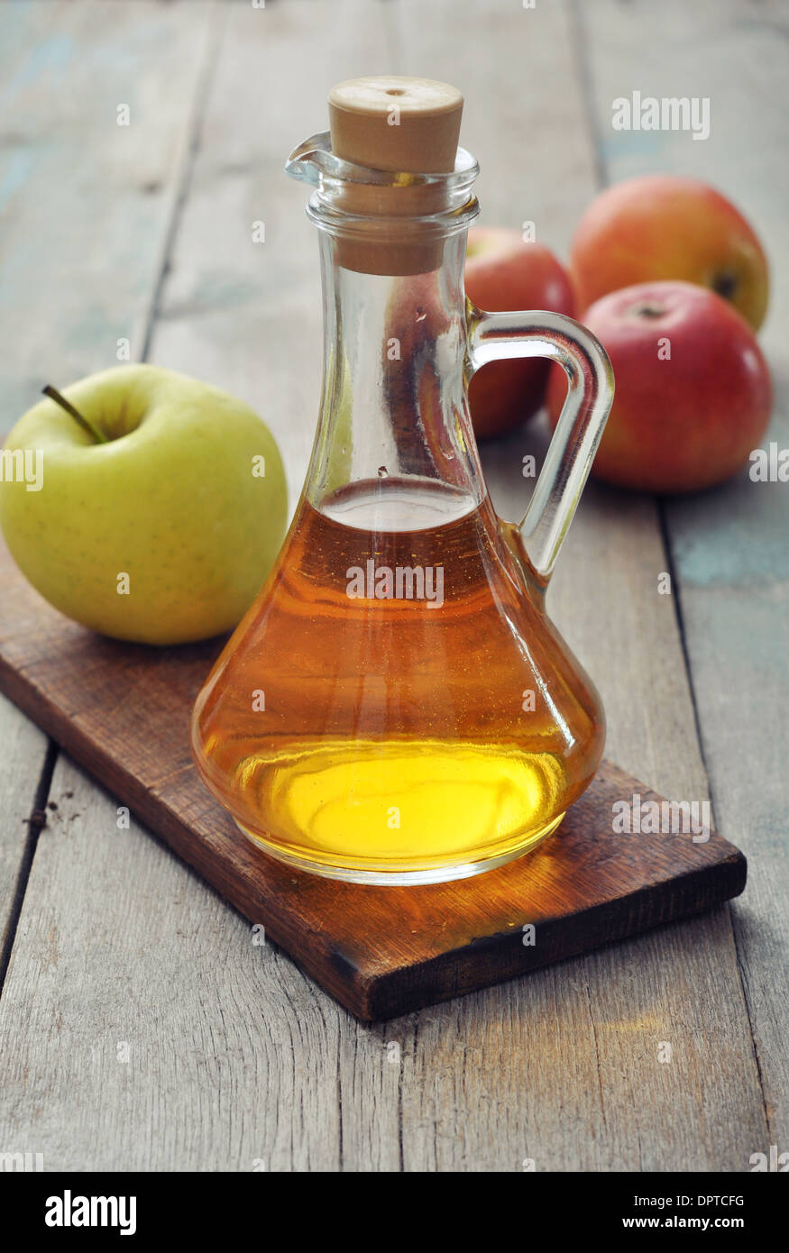 Apfelessig in Glasflasche und frischen Äpfeln Stockfoto