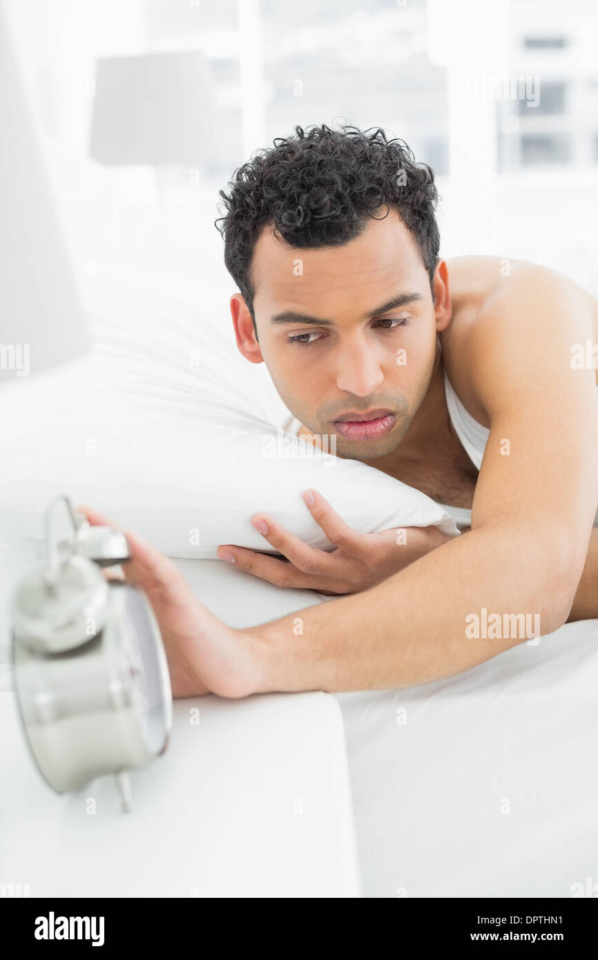 Verschlafene Mann streckte Hand mit Wecker Stockfoto