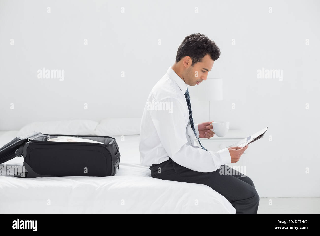 Geschäftsmann mit Tasse Zeitunglesen im Hotelzimmer Stockfoto