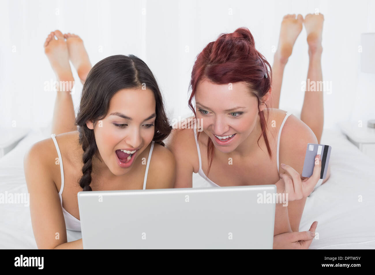 Fröhliche Freundinnen Online-Einkäufen im Bett Stockfoto