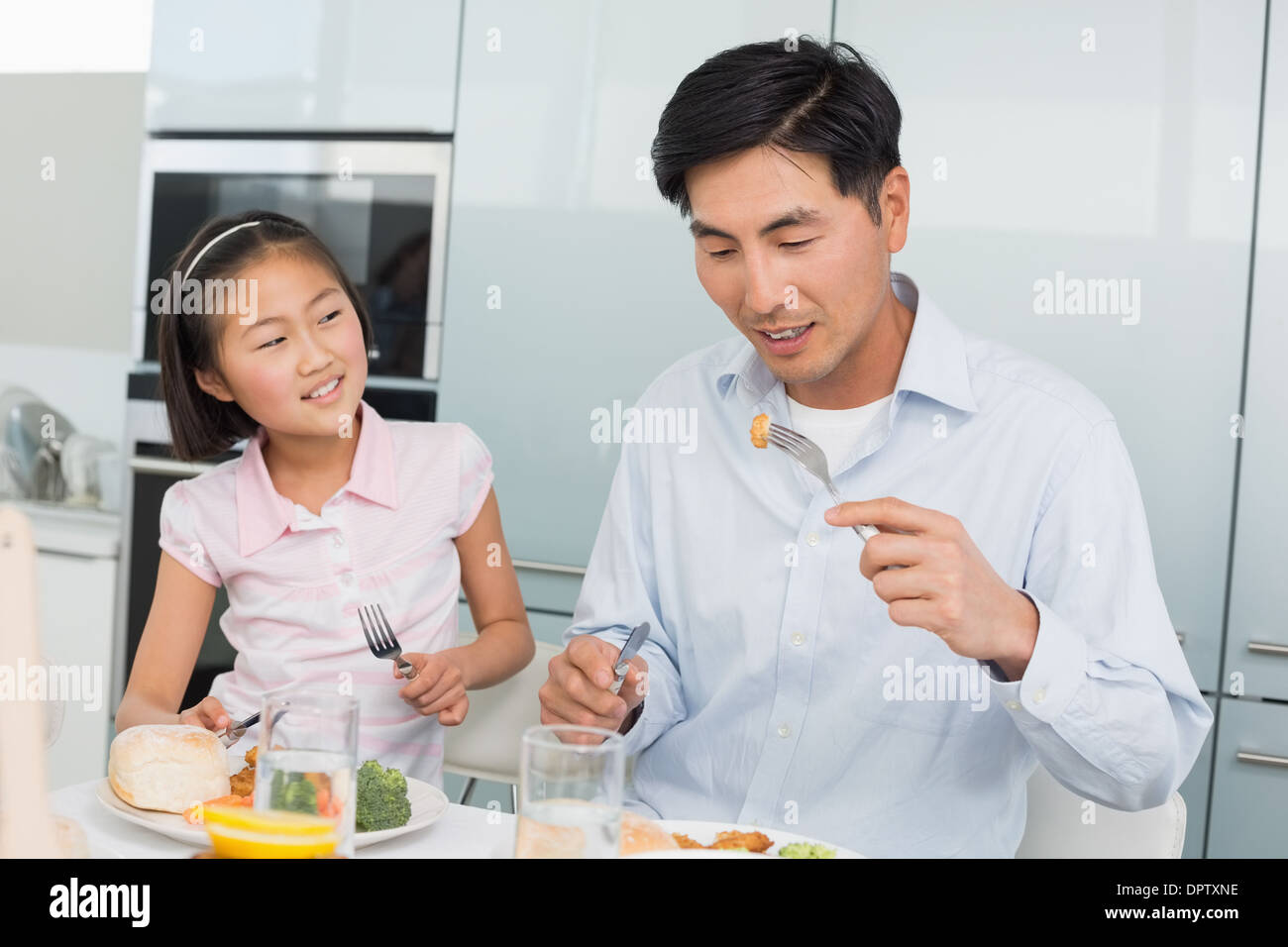 Kleine Mädchen beobachten Vater Essen mit einer Gabel in Küche Stockfoto
