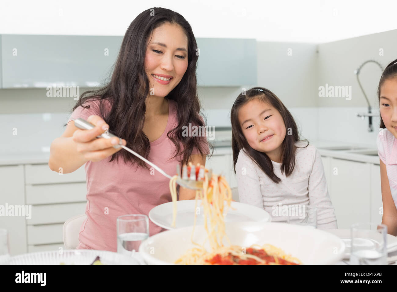 Mädchen beobachten glückliche Frau dienen Spaghetti in Küche Stockfoto